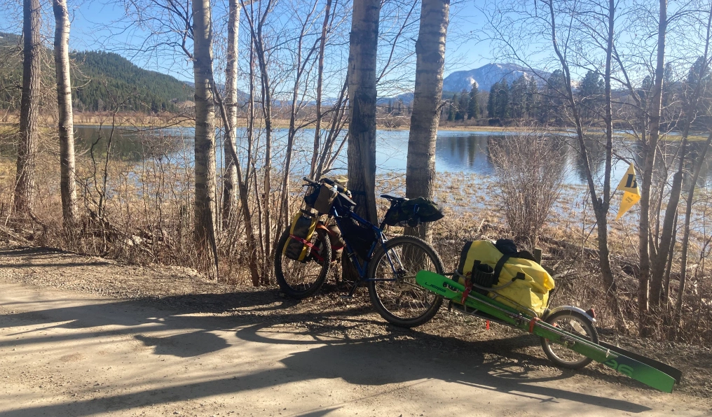 Loaded bikepacking setup with ski trailer beside a lake in the BC Kootenays