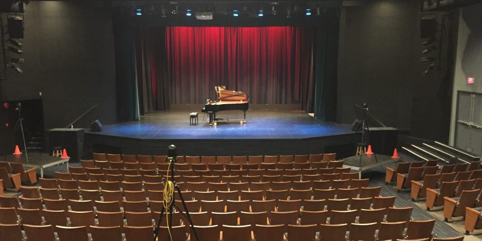 grand piano in the middle of the stage in an empty theatre