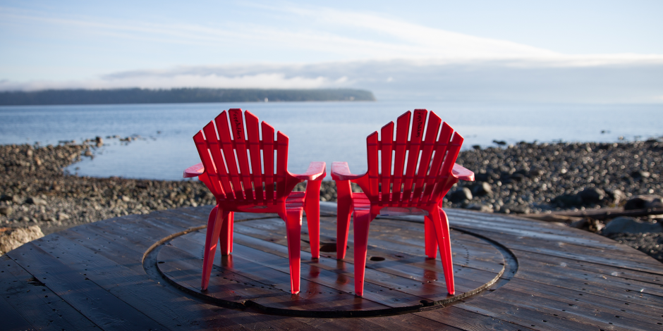 two red chairs sat in front of a serene ocean front