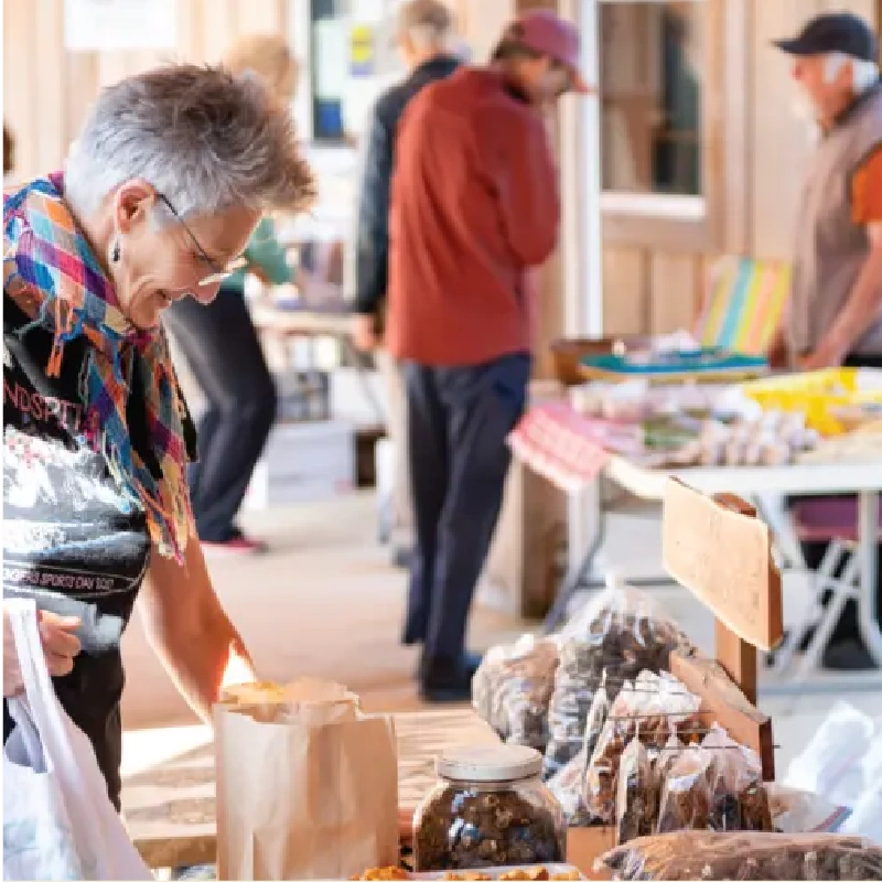 woman looks at a table of baked goods at the Campbell River Farmers Market