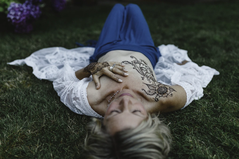 Healing through art Woman lying in garden with henna body art on chest as part of healing journey after mastectomy