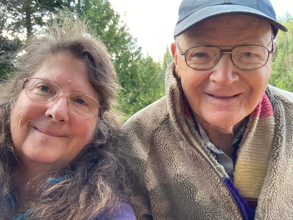 Billy Proctor and artist Yvonne Maximchuk smiling together outdoors in the Broughton Archipelago, wearing glasses and warm fleece jackets