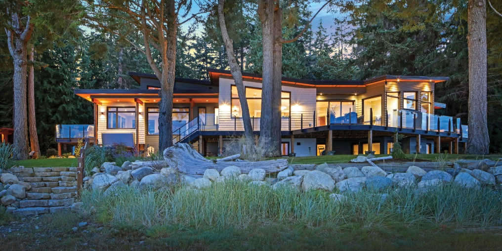 Modern waterfront home on Vancouver Island with coastal forest setting and natural landscaping at dusk