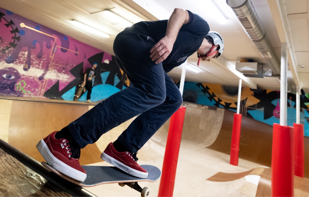 Adult skateboarder performing trick on red obstacle at LINC Youth Centre indoor skate park in Courtenay