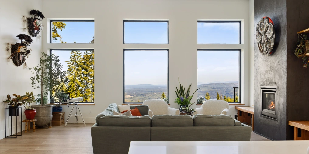 Open concept living room with floor-to-ceiling windows framing Comox Valley views and Indigenous art collection