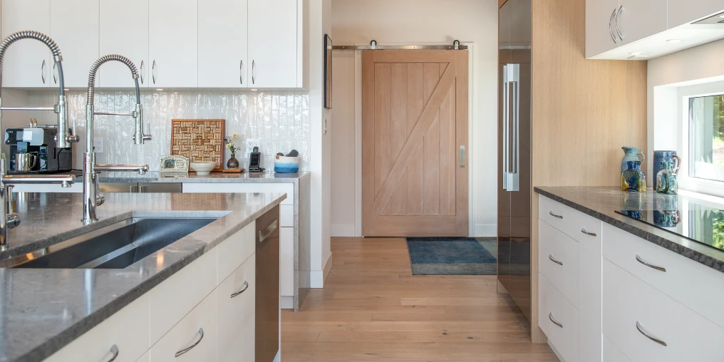 Modern kitchen with marble counters and white oak cabinets in Denman Island custom home