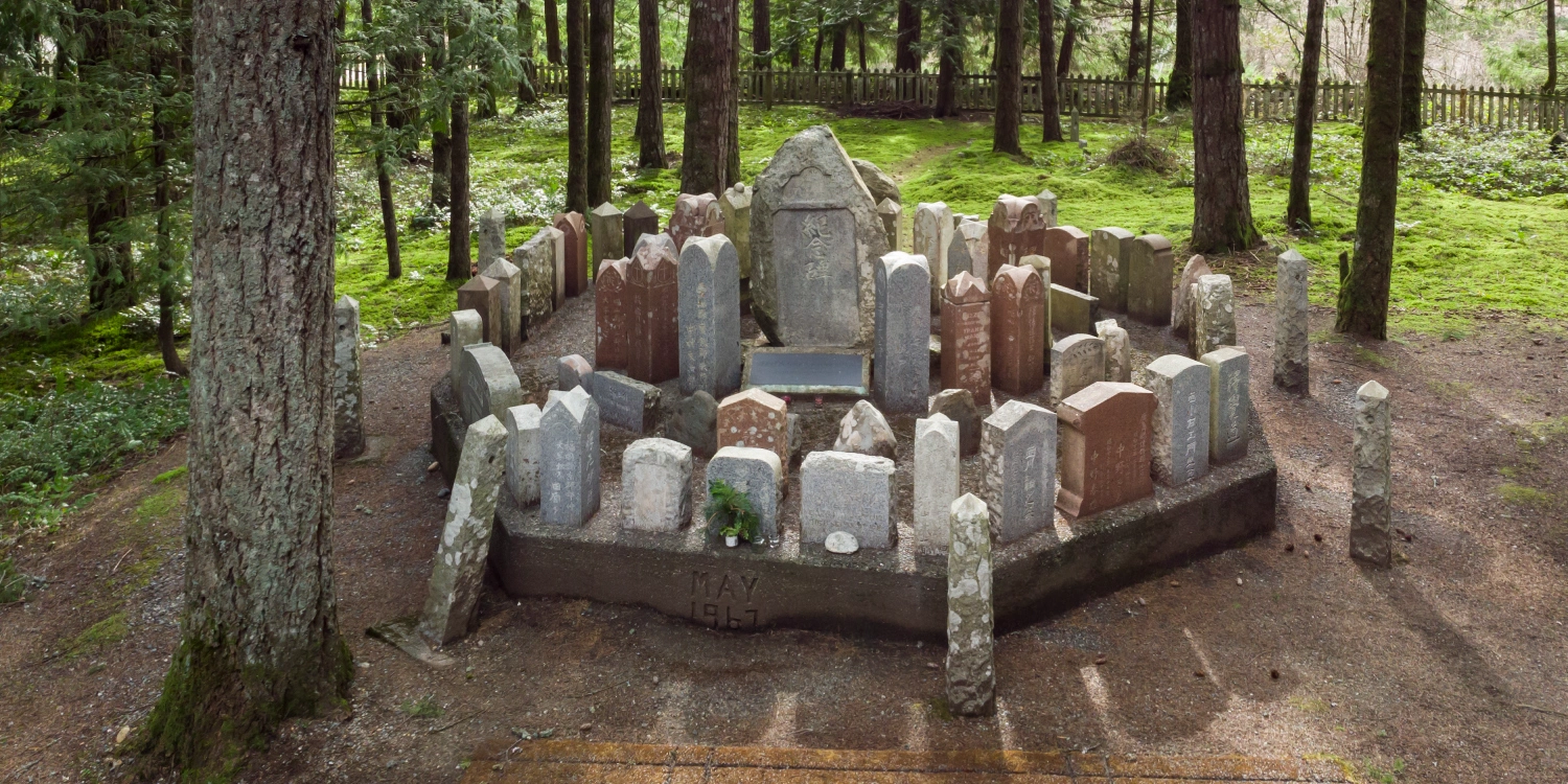 The 1967 memorial cairn at Cumberland's Japanese Canadian cemetery, surrounded by weathered headstones with Japanese inscriptions