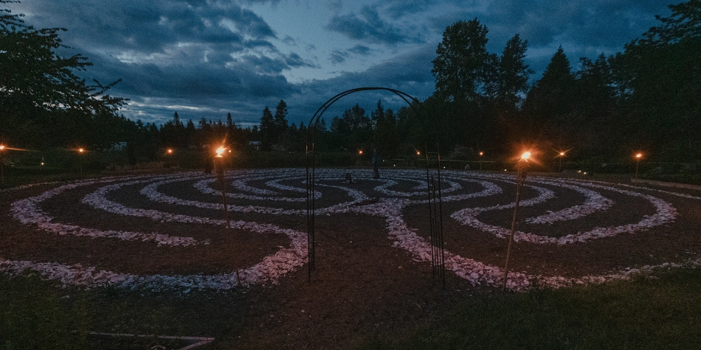A stone labyrinth lit by torches at dusk at Innisfree Farm Comox Valley