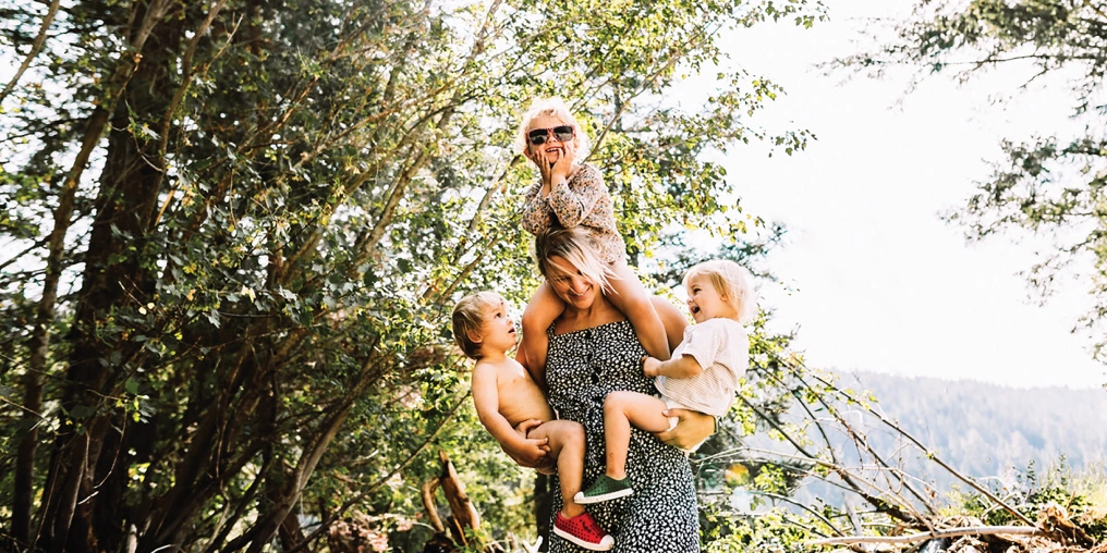A mother holds three young children among trees on a Vancouver Island outdoor adventure