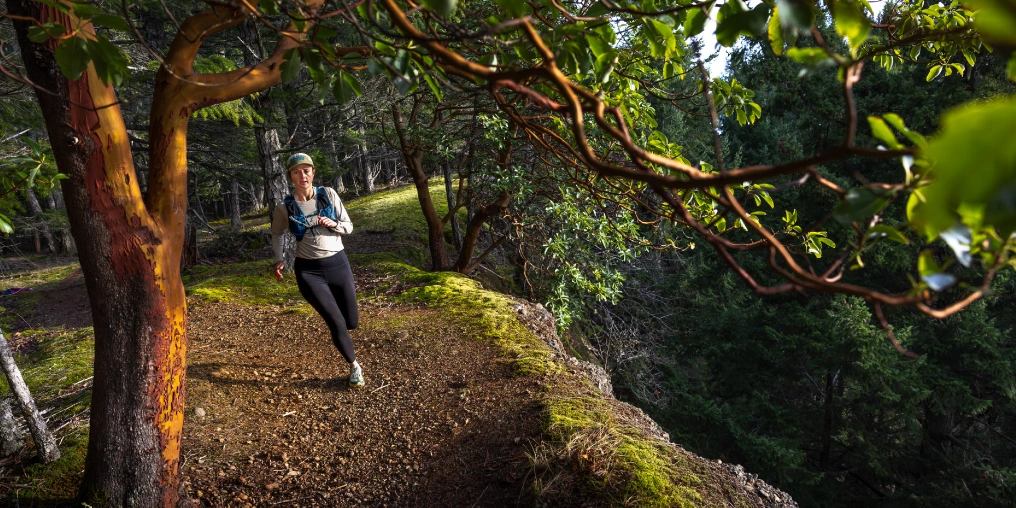 Trail runner on mossy singletrack during the Hornby Island Trail Race, arbutus trees overhead