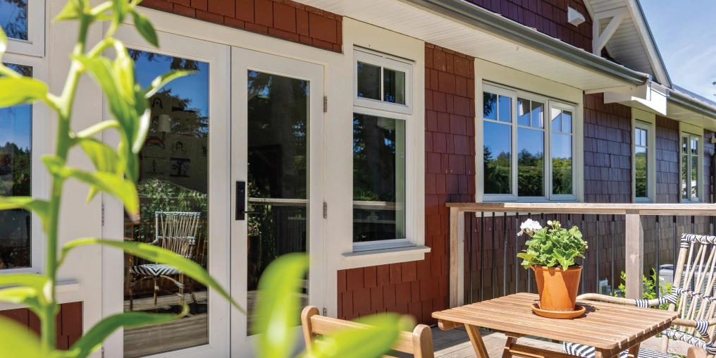 Restored farmhouse exterior with french doors and cedar shingle siding