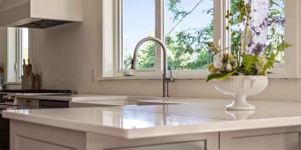 Renovated farmhouse kitchen with white island, undermount sink, and garden view window