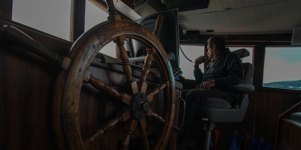 A man speaks onto the radio from the wheelhouse of his boat