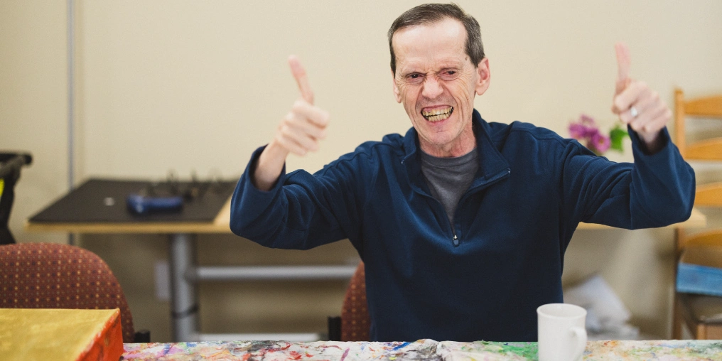 A L'Arche community member gives a thumbs up during an art activity