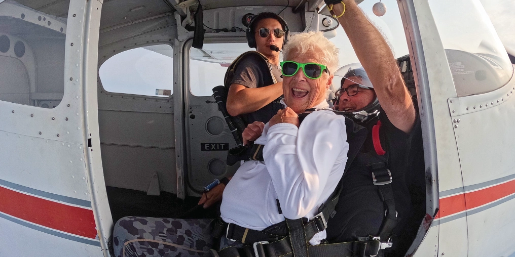 Celebrating 80 years with a tandem skydive Jill harnessed in tandem aboard the plane before her skydive over Nanoose Bay