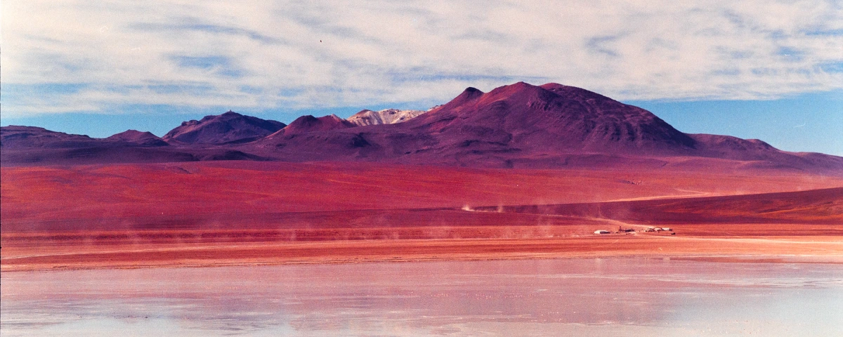 eric-overhoff-la-fronterra Snow-capped Patagonian mountains beyond a fenced grassland at golden hour