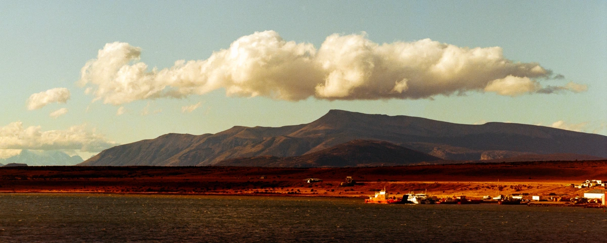 eric-overhoff-puerto-natales-chile Fishing boats docked along the waterfront in Puerto Natales, Chile, with mountains behind