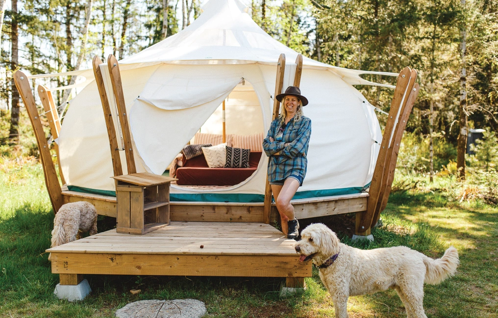 Agritourism - A key to farm viability on Vancouver Island A woman leans against a glamping yurt at Smith Lake Farm on Vancouver Island, with two dogs nearby