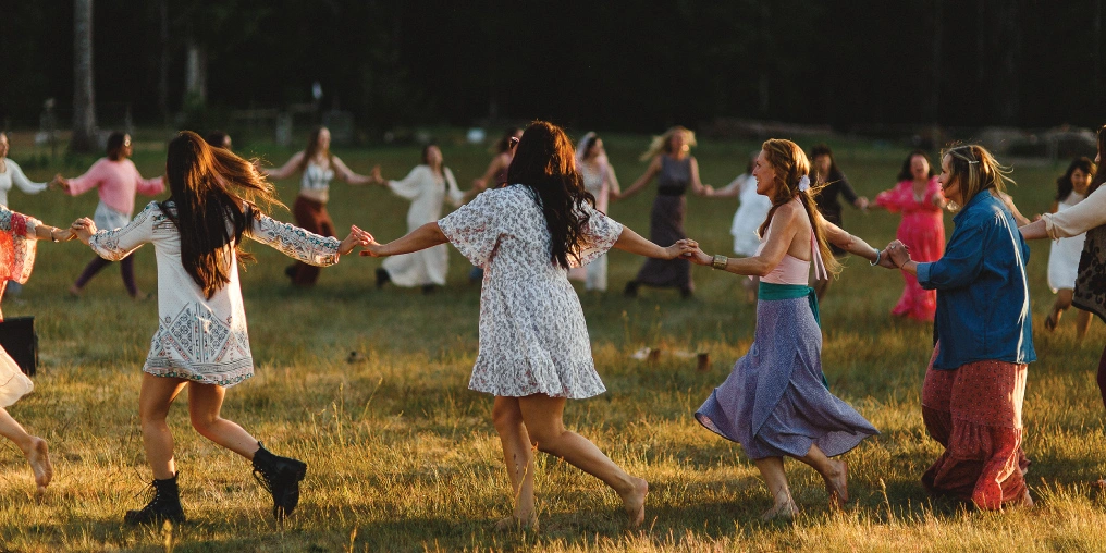 Agritourism - A key to farm viability on Vancouver Island A group of women hold hands in a circle during an outdoor wellness gathering at golden hour
