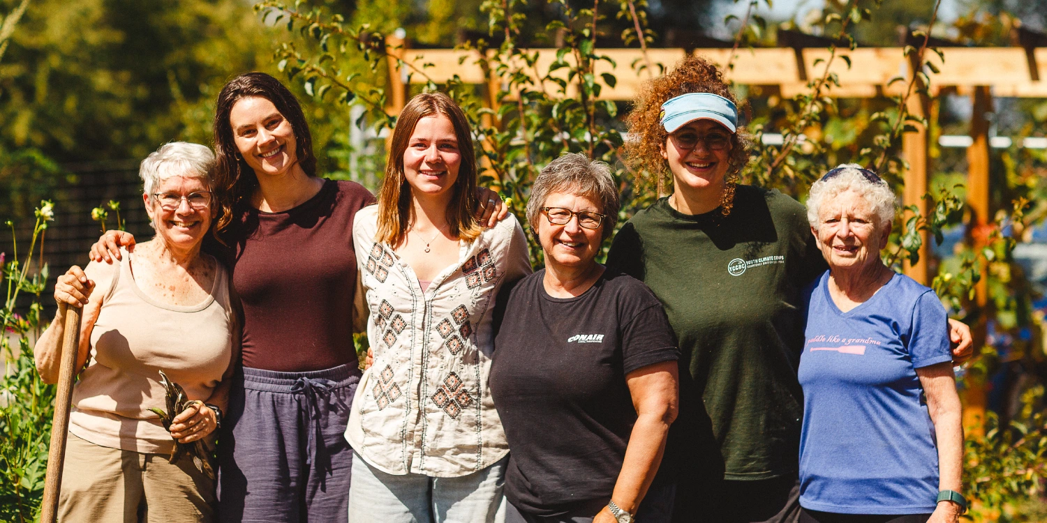 lush-valley-volunteers-group-portrait Six LUSH Valley volunteers of different generations smile with arms around each other in a sunlit community garden